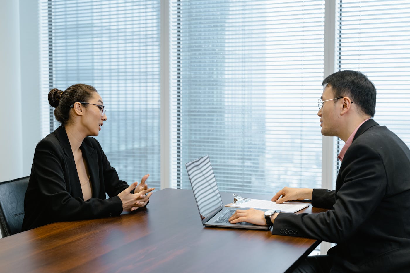 Two business leaders in a focused discussion across a conference table.