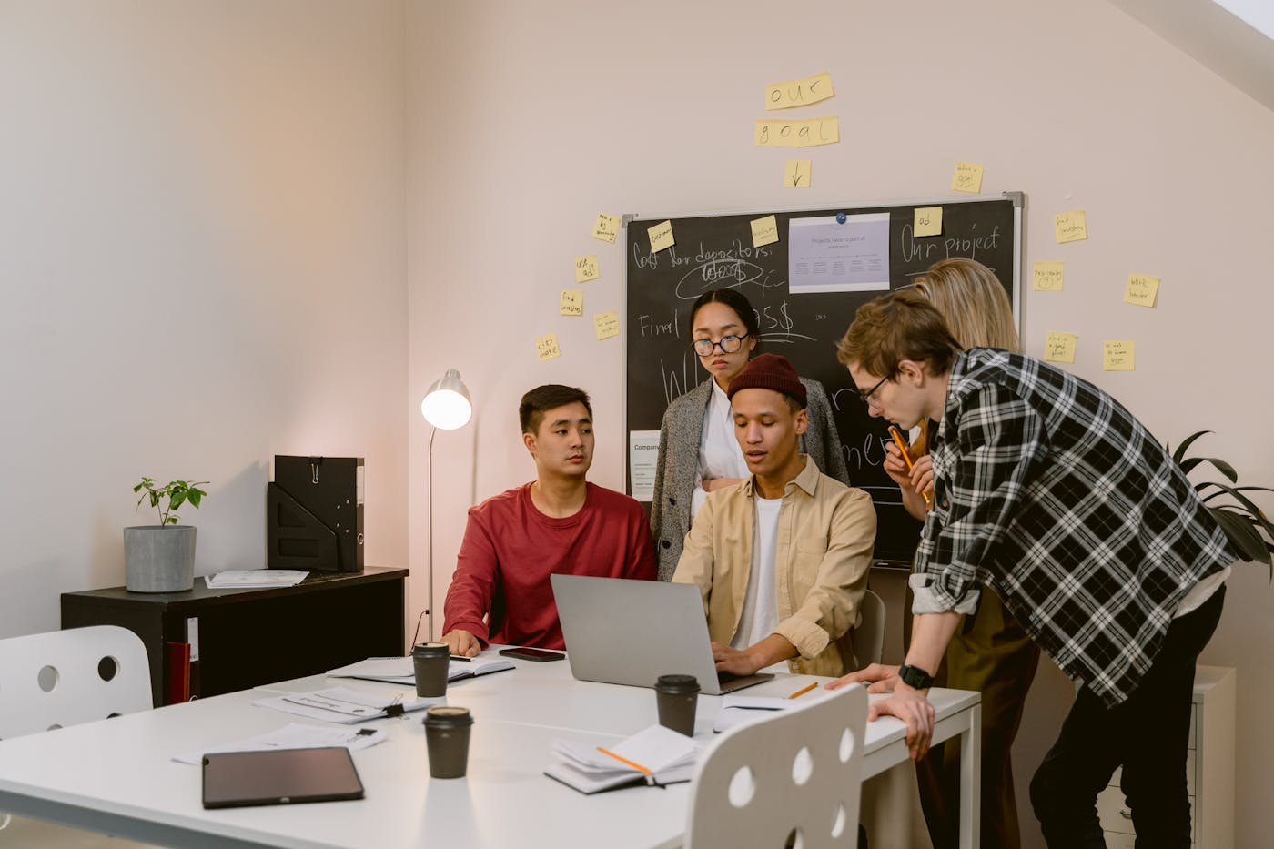 A cross-functional office team gathered around a laptop during a working discussion.