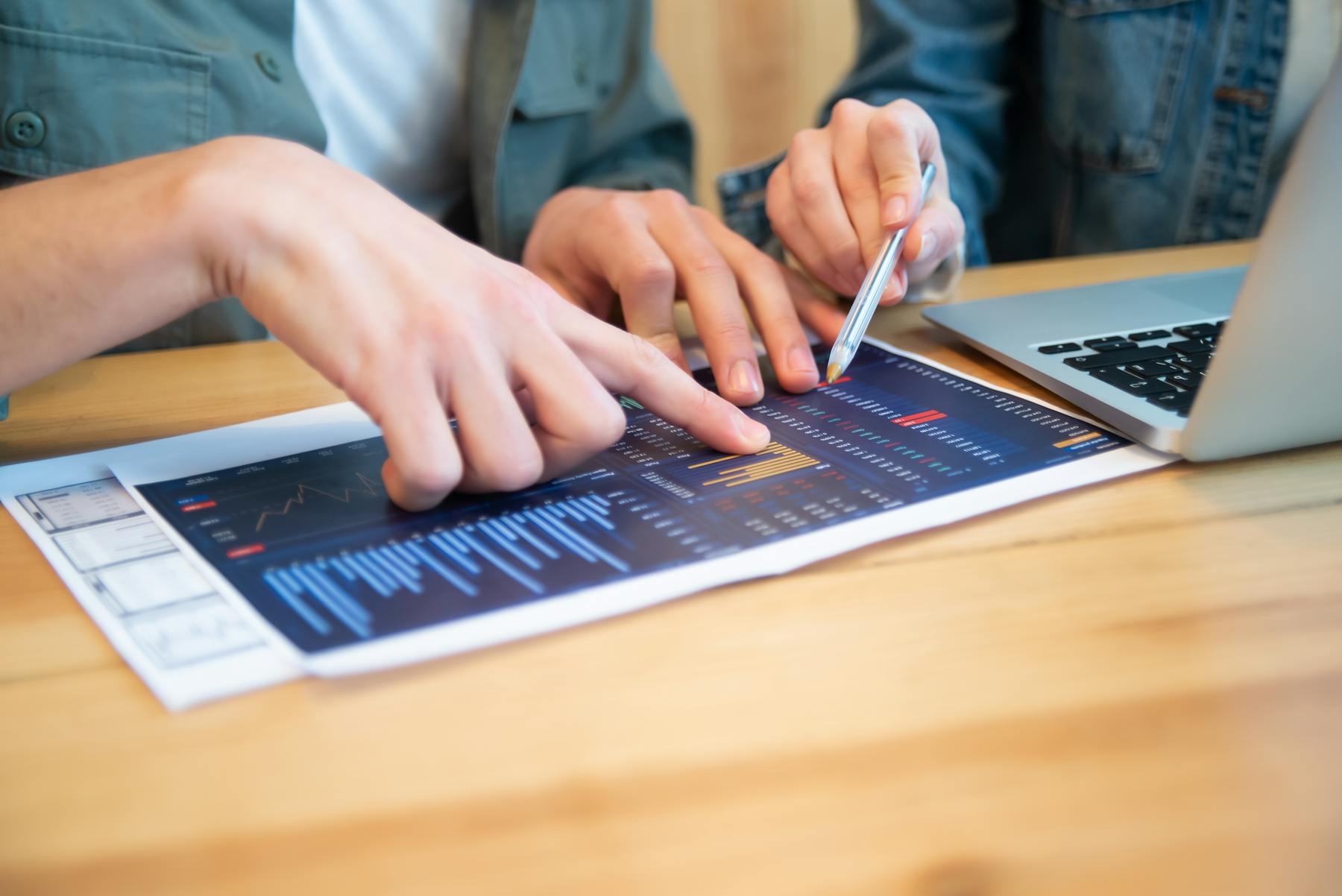Professionals reviewing analytical charts beside a laptop during a working session.
