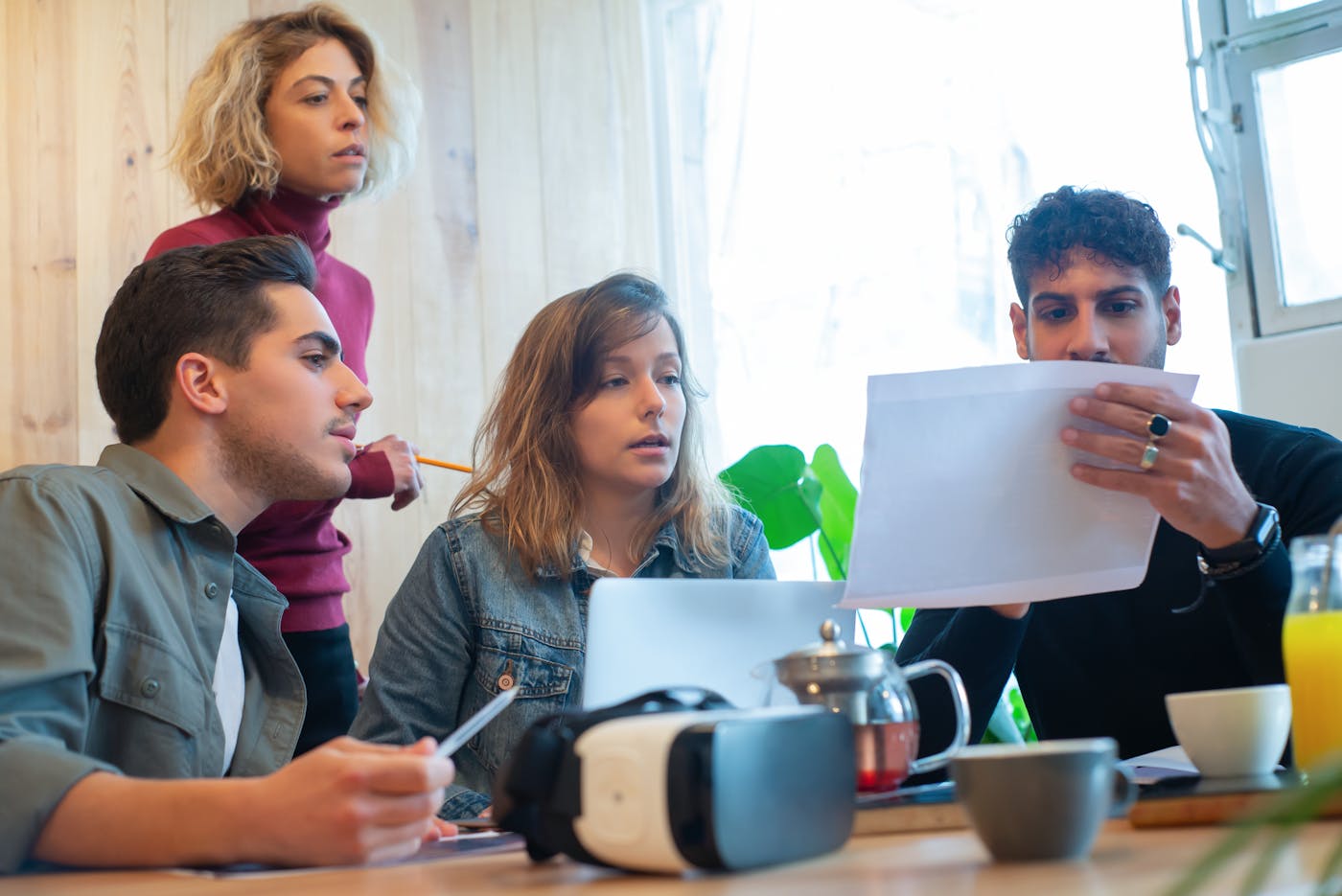 Business team reviewing a printed proposal together beside a virtual reality headset.