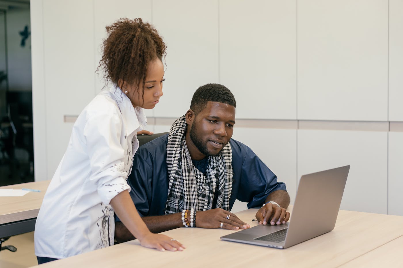 Two professionals reviewing work on a laptop in a focused office discussion.